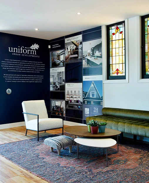 Uniform showroom seating area with display wall, stained glass windows, chairs, tables and patterned rug.